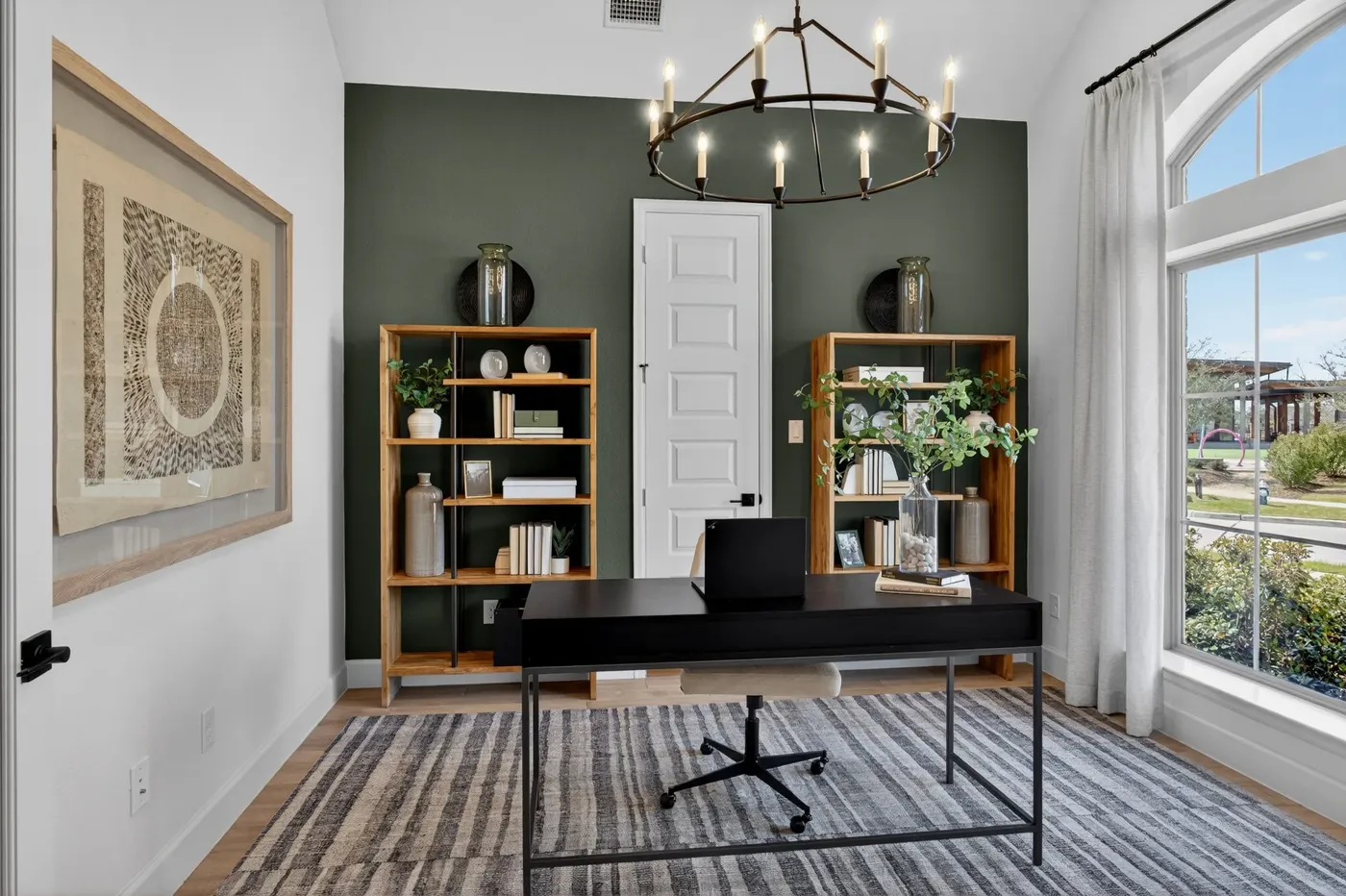 Home office with a dark green wall and iron chandelier